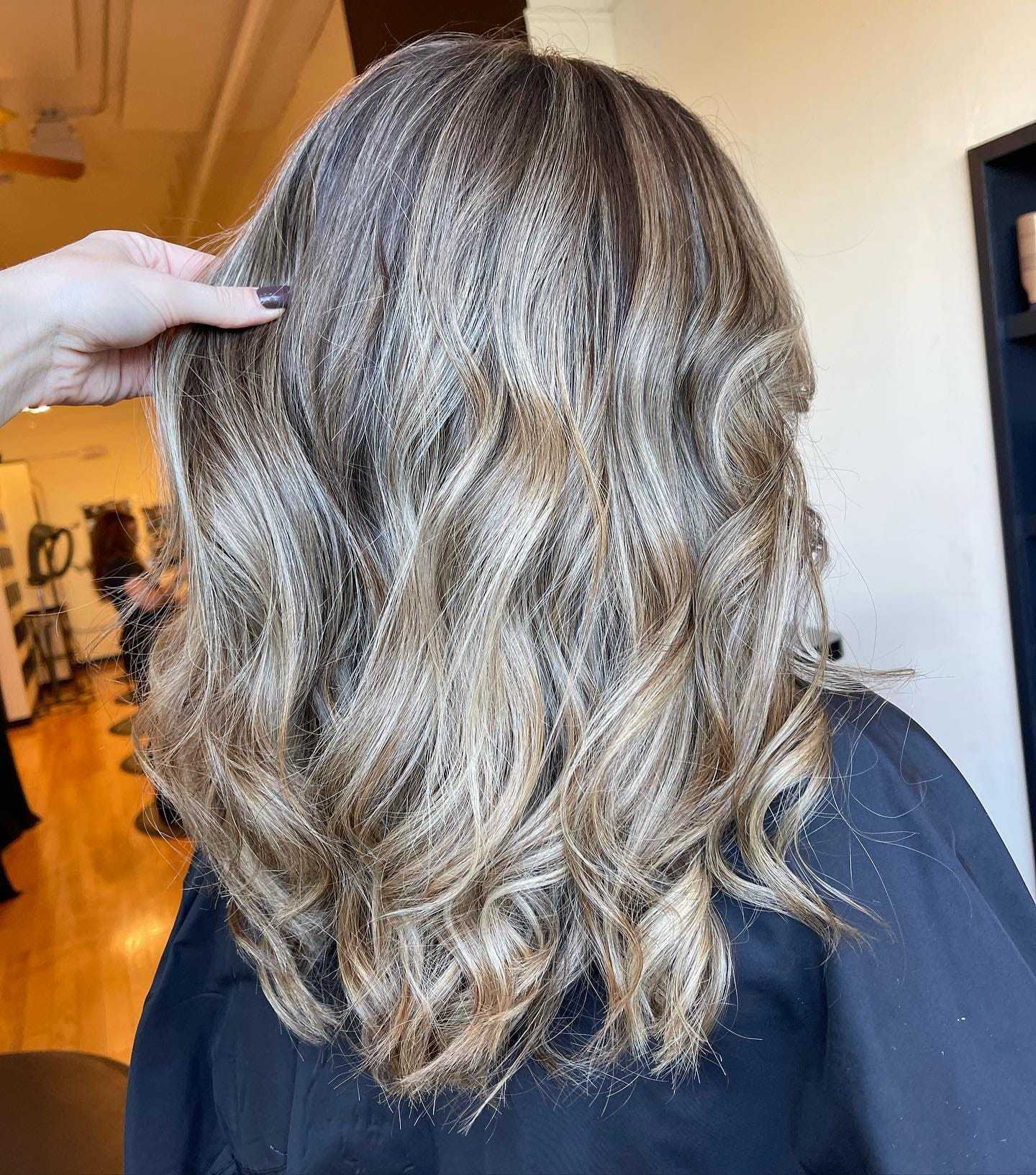 Wavy blond hair styled in loose curls from the back view.