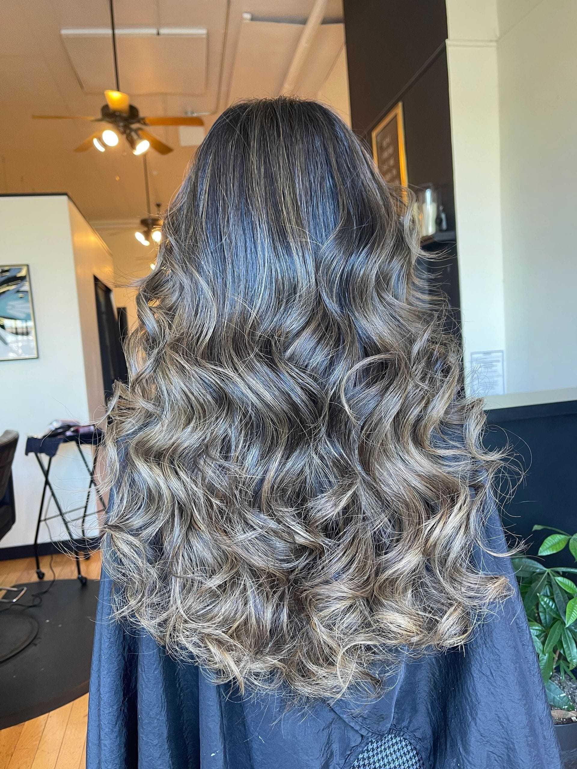 Long, wavy brown hair styled in soft curls at a salon.
